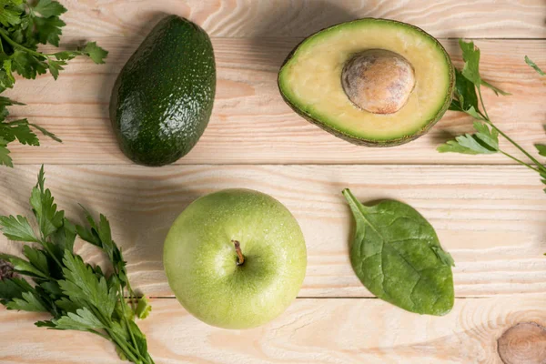 Avocado mit Petersilie und Apfel auf Holztisch — Stockfoto