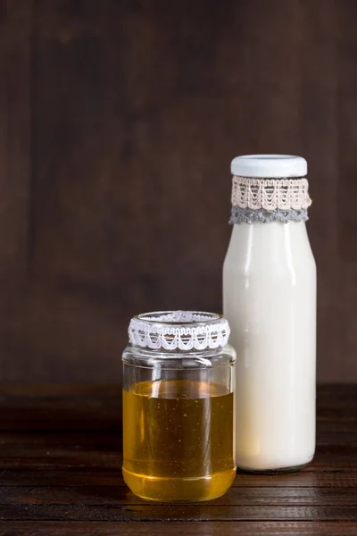 Botella de vidrio de leche con miel en frasco - foto de stock