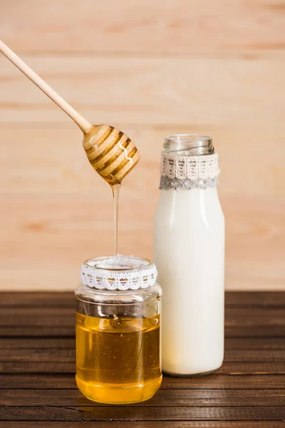 Glass bottle of milk with honey in jar — Stock Photo