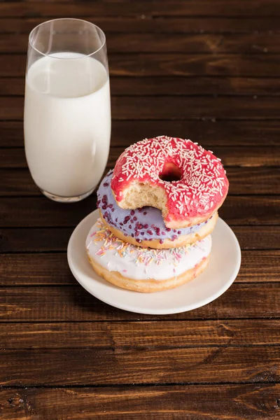 Glass of milk with donuts on plate — Stock Photo