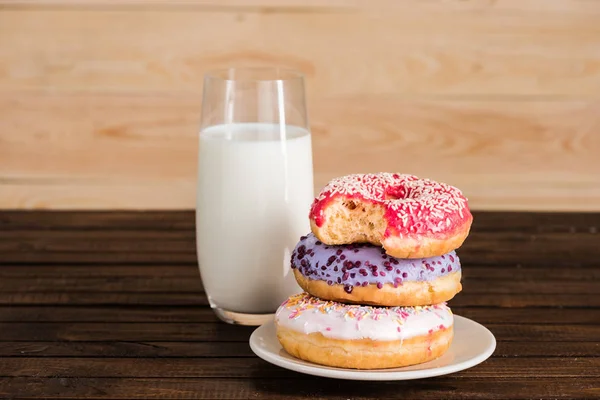 Vidro de leite com rosquinhas na placa — Fotografia de Stock