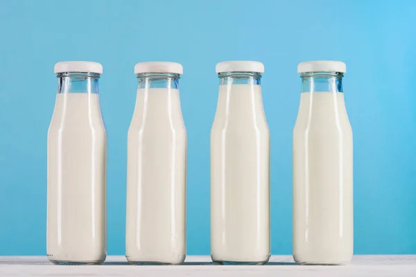 Fila di bottiglie di vetro con latte sul tavolo — Foto stock