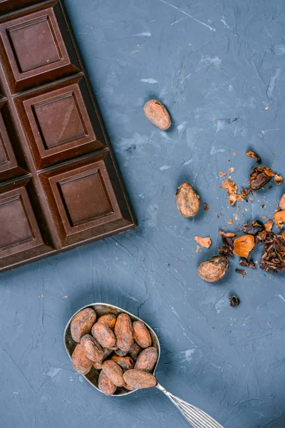 Barra de chocolate e colher com grãos de cacau — Fotografia de Stock