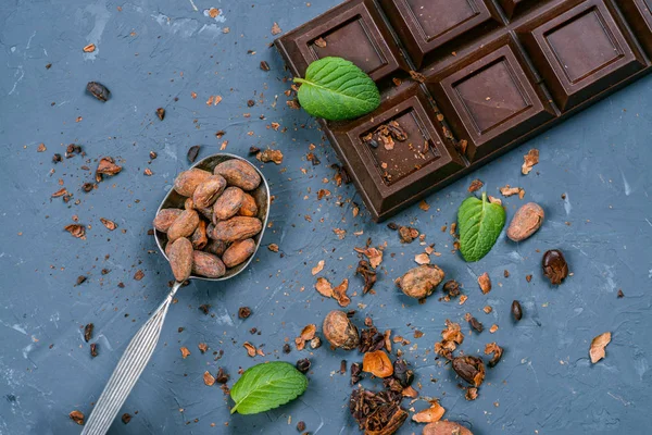 Barre de chocolat et cuillère avec des fèves de cacao — Photo de stock