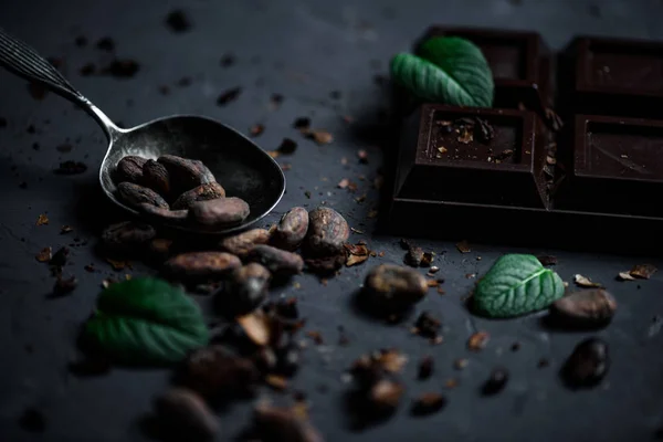 Chocolate bar and spoon with cocoa beans — Stock Photo