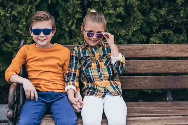 Niños adorables sentados en el banco en el parque - foto de stock