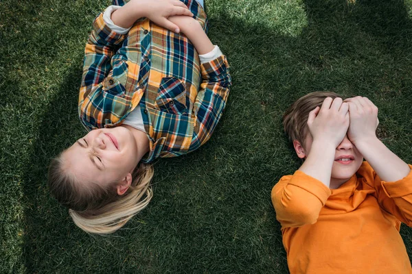 Adorable kids sunbathing while lying on grass — Stock Photo