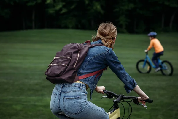 Mujer con mochila a caballo bicicleta en el parque - foto de stock