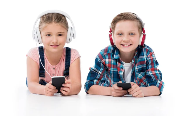 Niños usando teléfonos inteligentes en auriculares - foto de stock