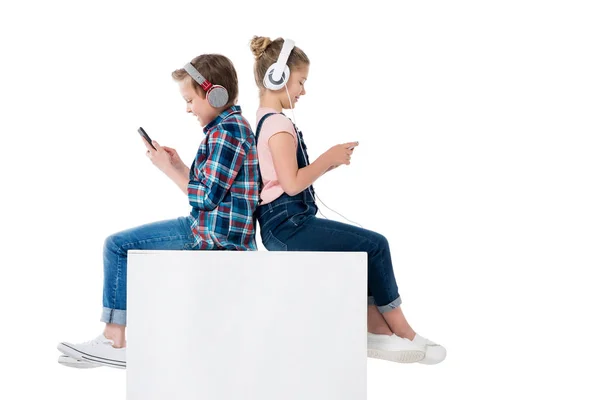 Niños usando teléfonos inteligentes en auriculares - foto de stock