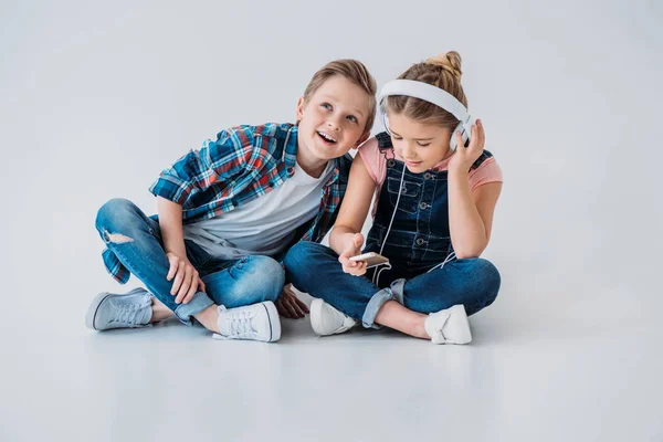 Adorables niños escuchando música en auriculares - foto de stock