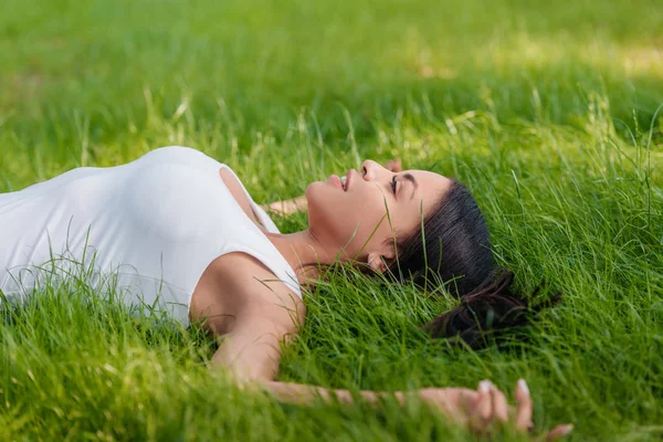 Жінка лежить на зеленій траві — стокове фото