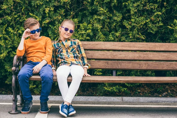 Niños sentados en el banco - foto de stock