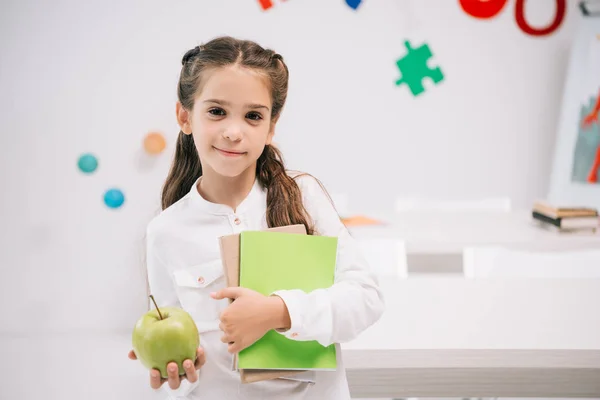 Colegiala con manzana y libros de texto - foto de stock