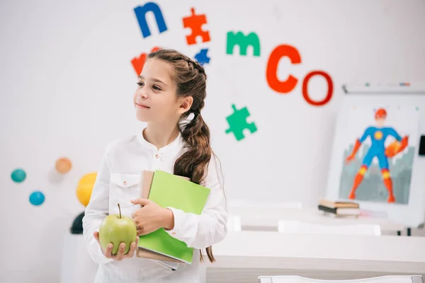 Schulmädchen mit Apfel und Schulbüchern — Stockfoto