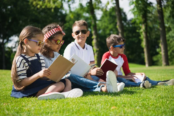 Children reading books in park — Stock Photo