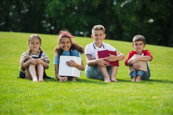 Children reading books in park — Stock Photo