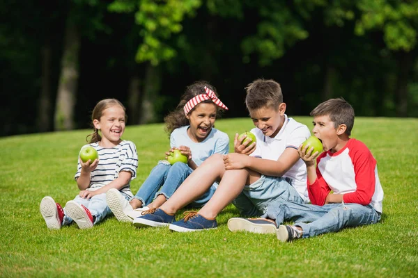Niños comiendo manzanas en el parque - foto de stock
