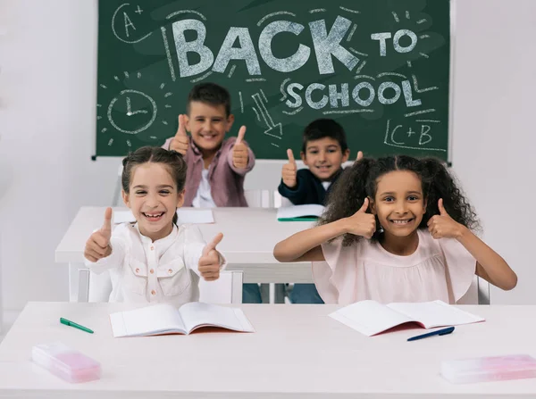 Multiethnic schoolkids with thumbs up — Stock Photo