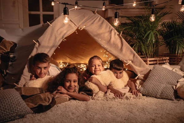 Crianças multiculturais descansando na tenda em casa — Fotografia de Stock