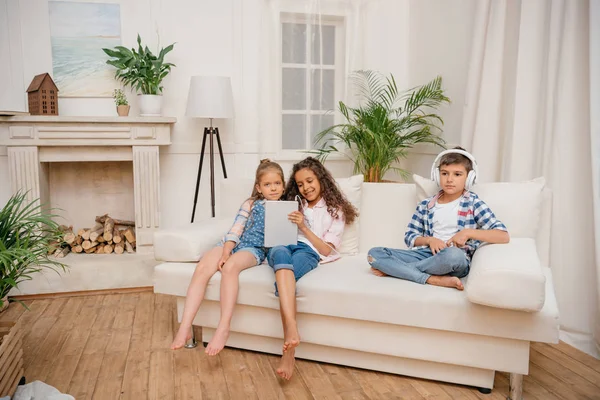 Niños con dispositivos digitales en casa - foto de stock