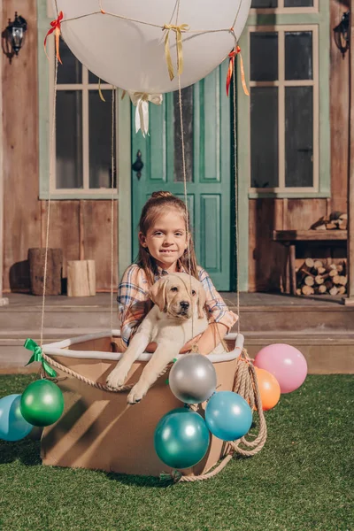 Girl with puppy in air balloon box — Stock Photo