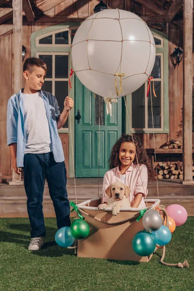 Girl with puppy in air balloon box — Stock Photo