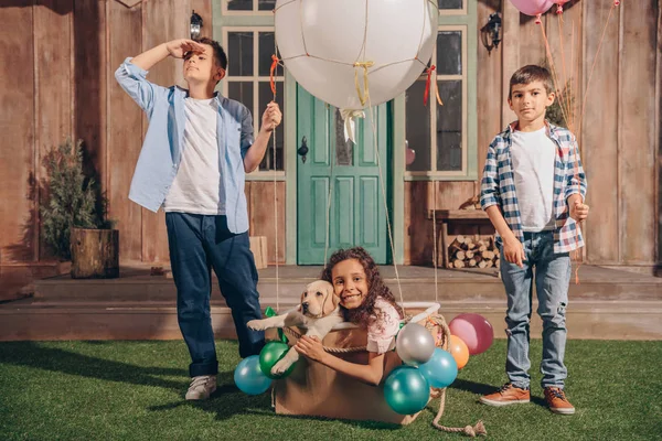 Girl with puppy in air balloon box — Stock Photo