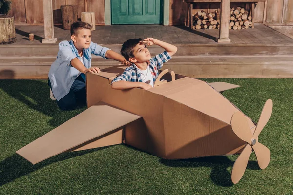 Boys playing with cardboard airplane — Stock Photo