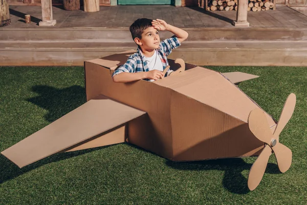 Мальчик в картонном самолете — стоковое фото