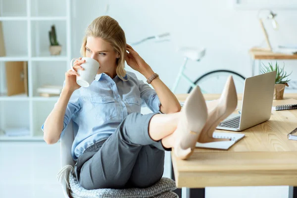 Businesswoman drinking coffee at workplace — Stock Photo