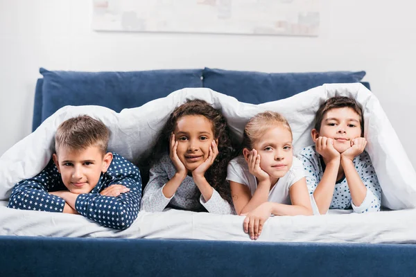 Bambini multiculturali sdraiati a letto — Foto stock