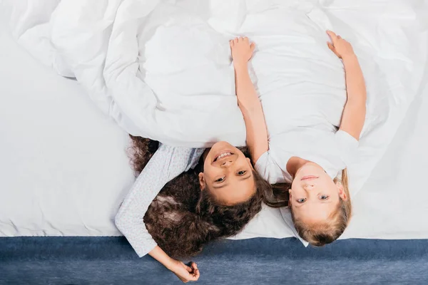 Meninas multiculturais deitado na cama — Fotografia de Stock