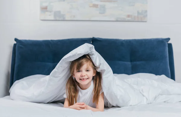 Девушка прячется под одеялом — стоковое фото