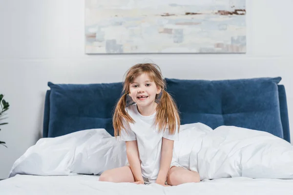 Little girl sitting on bed — Stock Photo