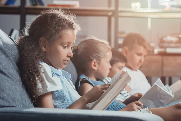 Niños multiculturales leyendo libros - foto de stock