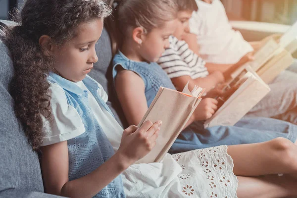 Niños multiculturales leyendo libros - foto de stock