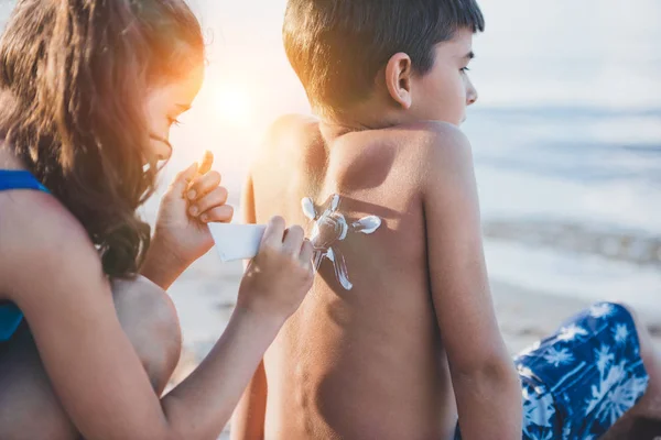 Ragazza che applica la crema solare sul ragazzo — Foto stock