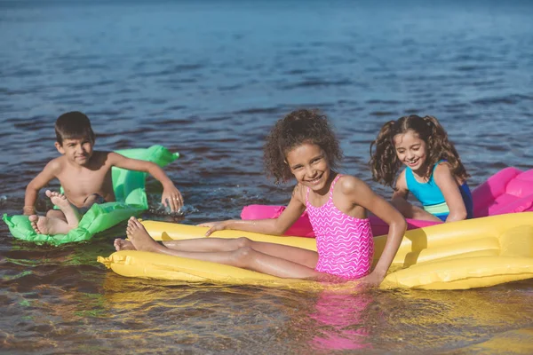 Enfants multiethniques sur matelas gonflables — Photo de stock