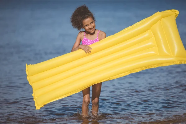 Chica afroamericana con colchón inflable - foto de stock