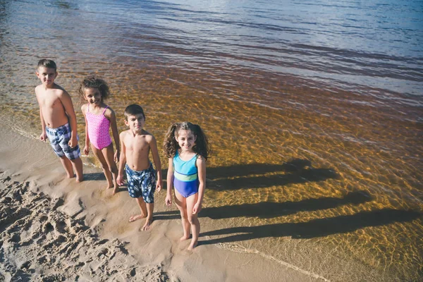 Niños multiculturales en trajes de baño en la playa - foto de stock