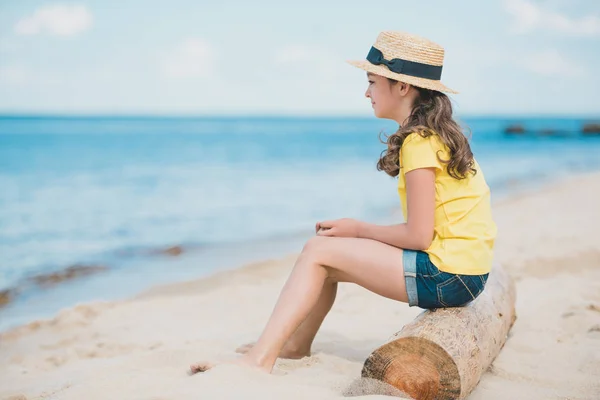 Petite fille assise sur la plage — Photo de stock