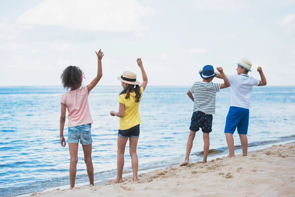 Niños lanzando piedras a la orilla del mar - foto de stock