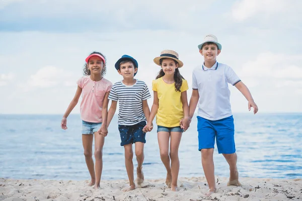Niños multiculturales caminando en la playa - foto de stock