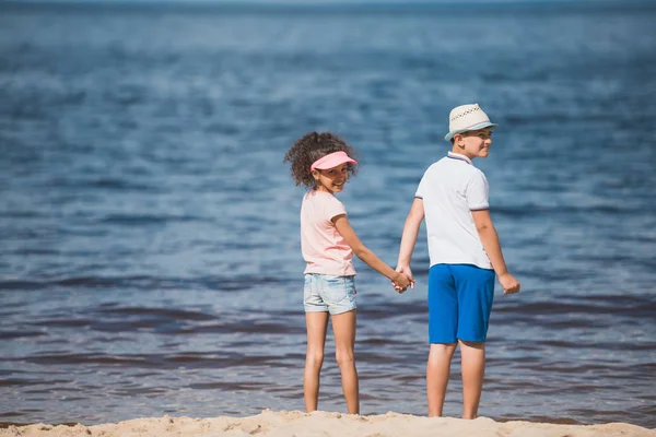 Multiethnic children standing at seaside — Stock Photo