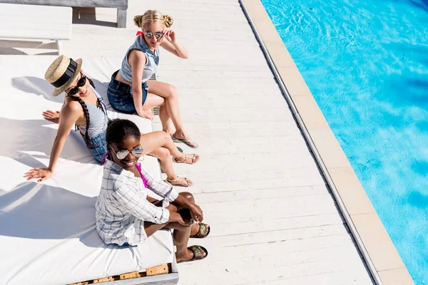 Mujeres multiétnicas cerca de la piscina en el complejo - foto de stock