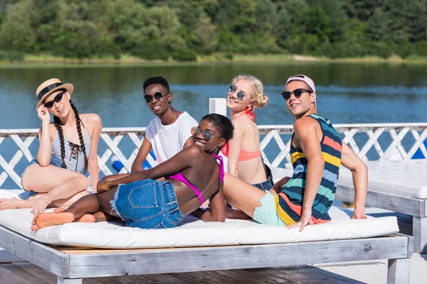 Amigos multiétnicos cerca de la piscina en el resort - foto de stock