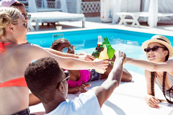 Amigos multiétnicos cerca de la piscina en el resort - foto de stock