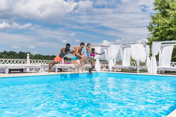 Gente multiétnica saltando a la piscina - foto de stock