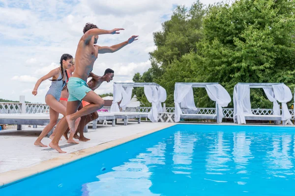Persone multietniche che saltano in piscina — Foto stock